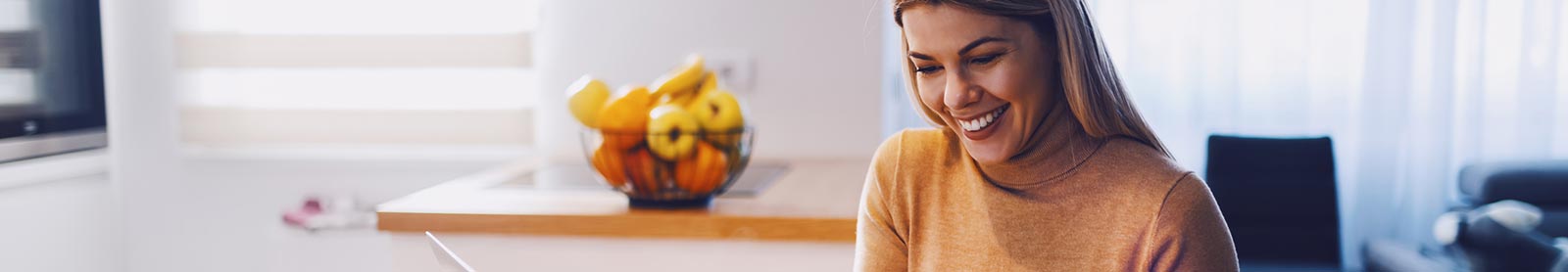 Lady in her kitchen using a laptop computer looking at finances